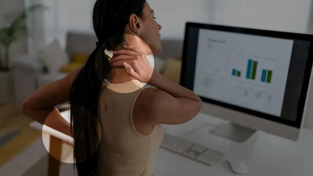 A woman at her desk holding a sore neck and lower back