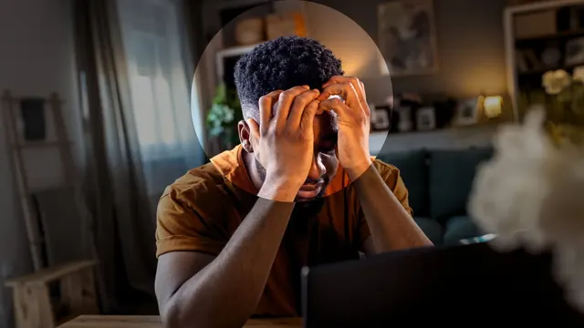 A man at a laptop rubbing his eyes